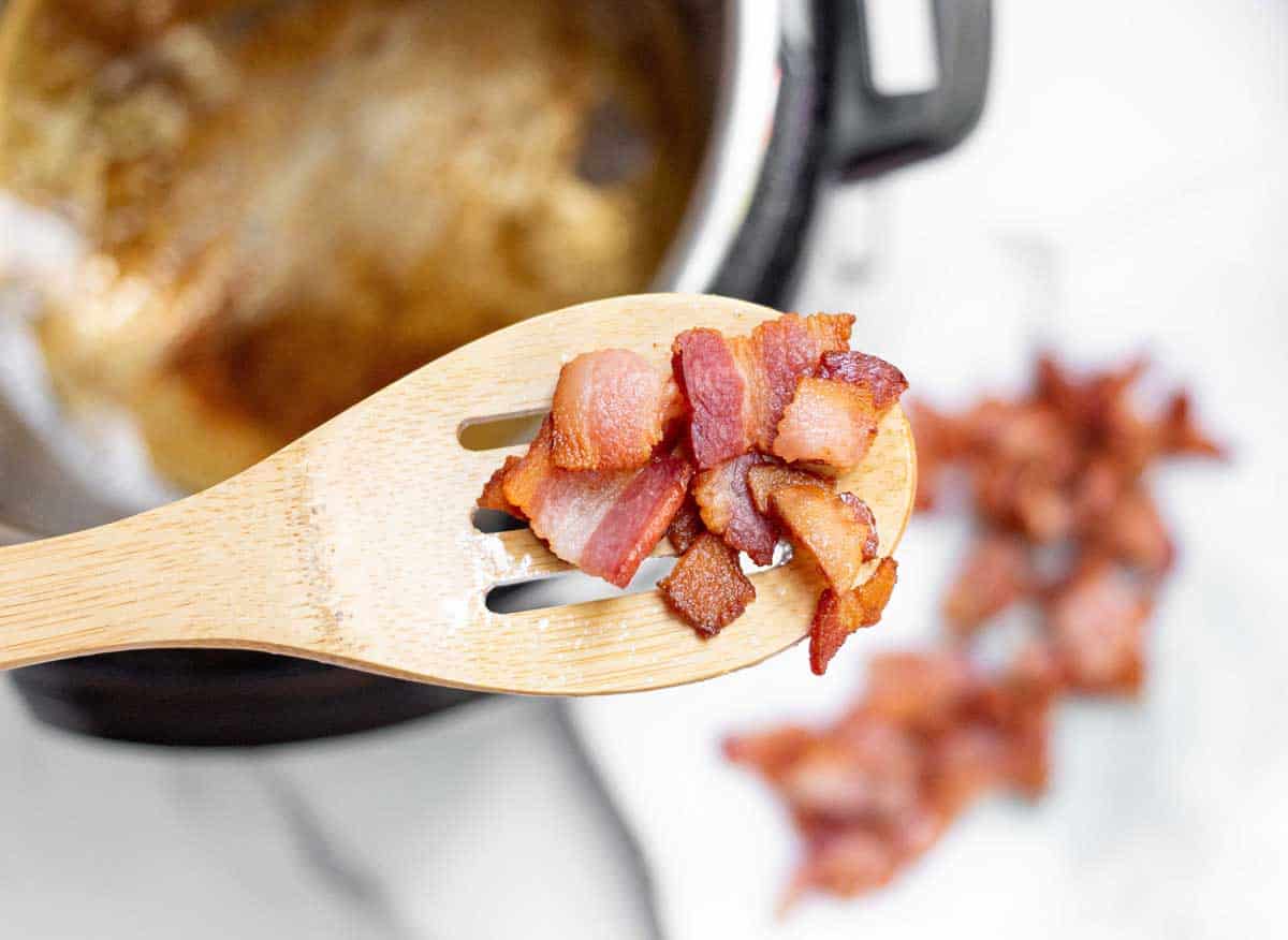 Cooked bacon chunks on a slotted spoon.