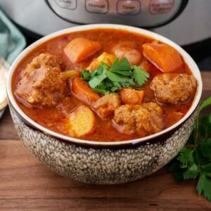 Bowl of Instant Pot meatball soup with chunky vegetables and fresh parsley.