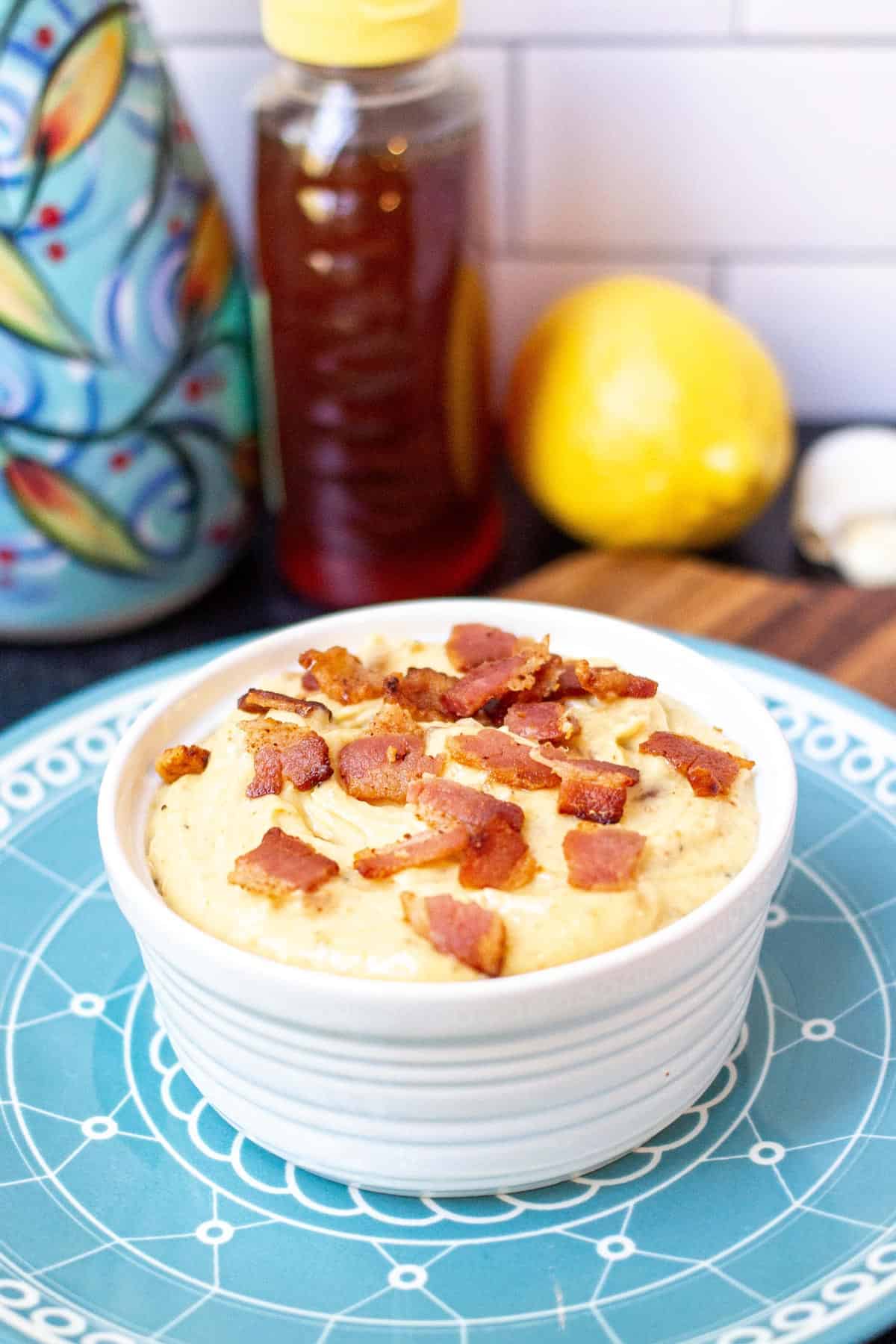 Small ramekin filled with bacon aioli topped with bacon bits.