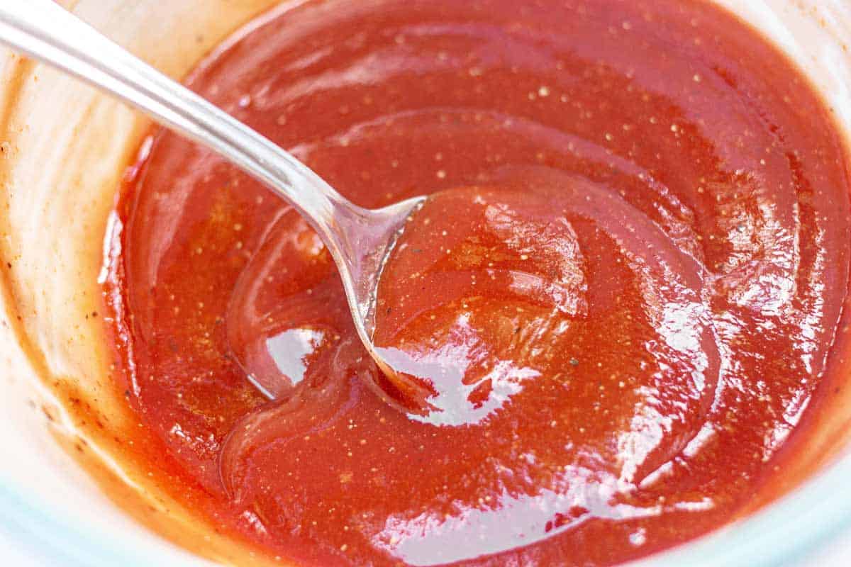 Meatloaf ketchup glaze in a small bowl with a spoon.