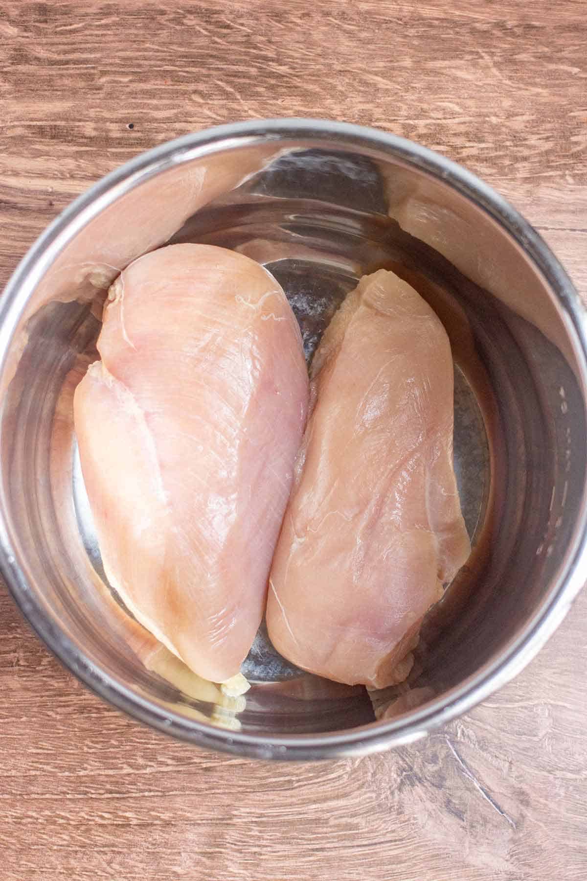 Two raw chicken breasts in an Instant Pot liner.