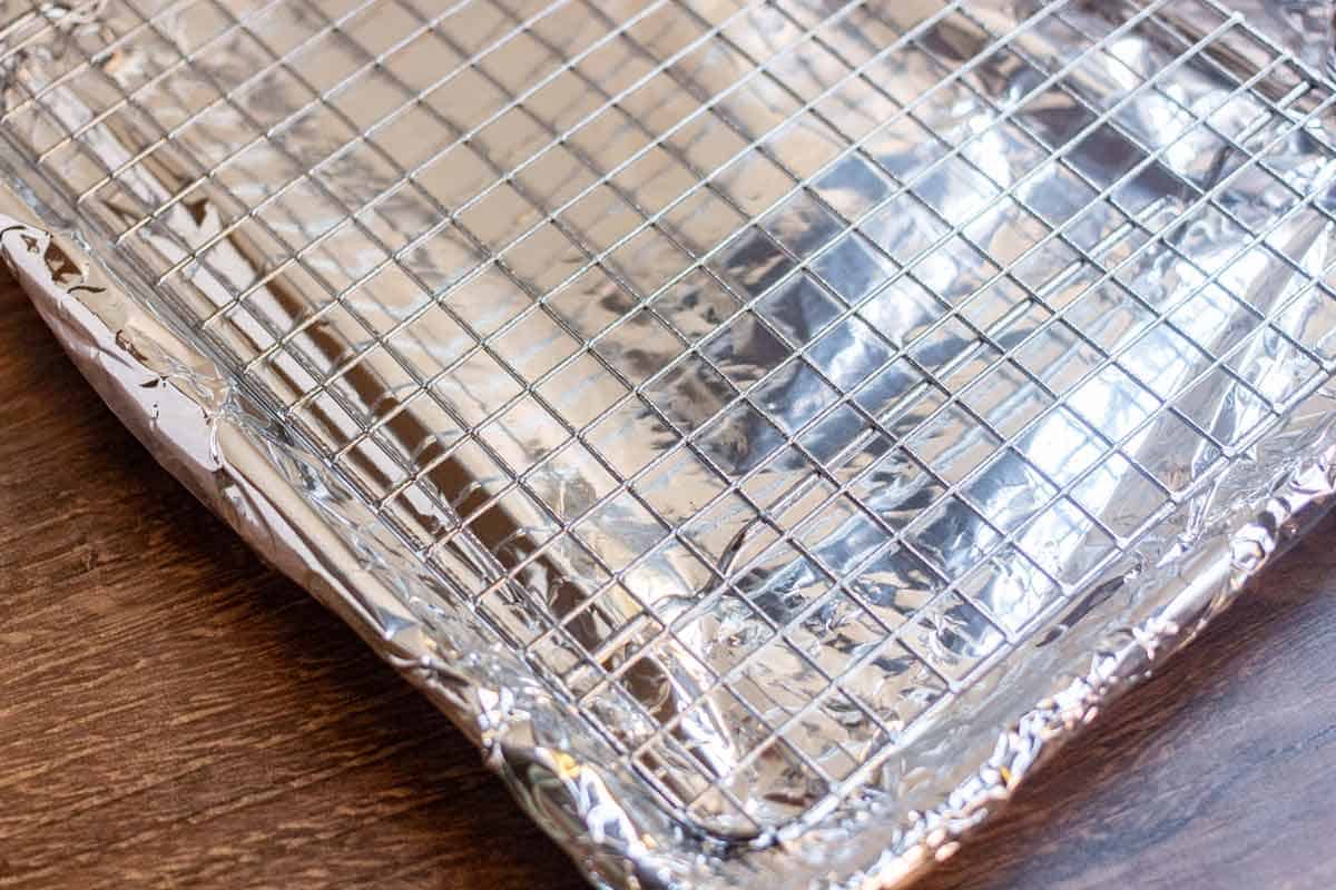 A wire rack on a baking tray that is covered in foil.