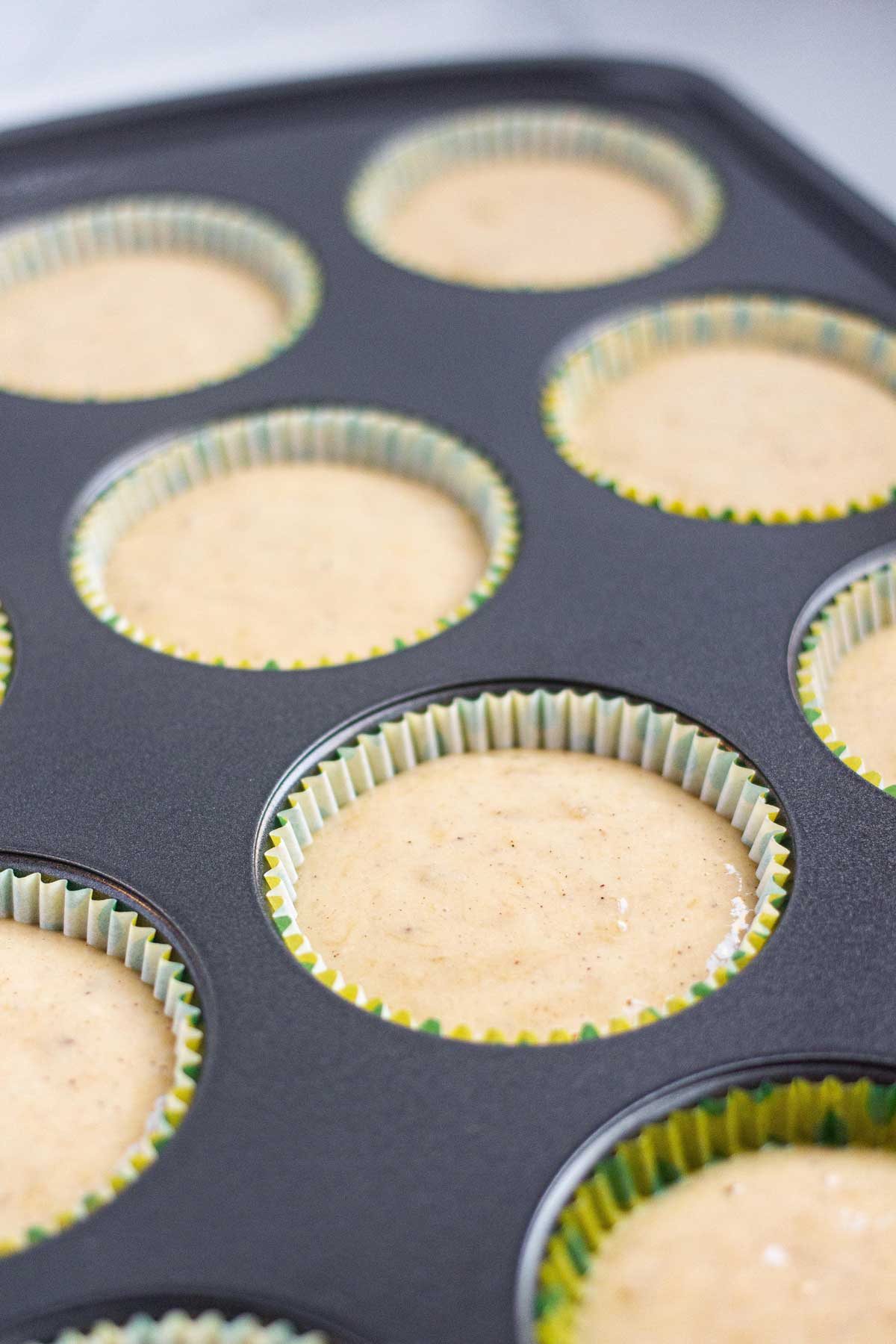 Muffin batter in baking cup inside a muffin baking pan.