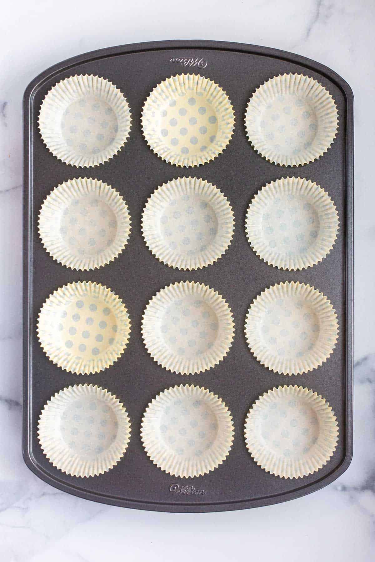 Paper baking cups sitting in a muffin baking pan.