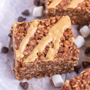 Close up of a chocolate peanut butter rice krispie treat with peanut butter drizzle on top.