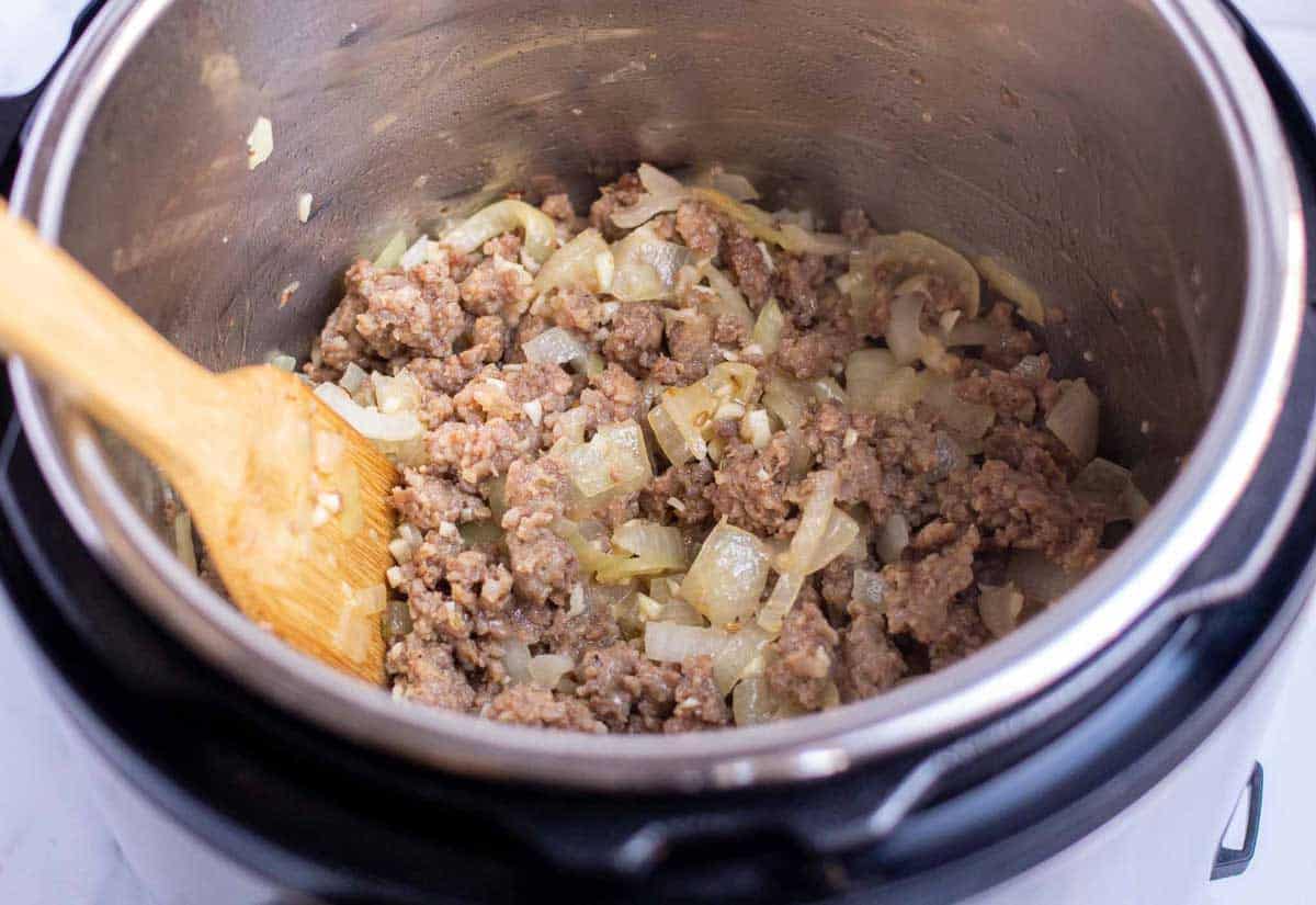 Browned Italian sausage with cooked diced onion and minced garlic in the Instant Pot.
