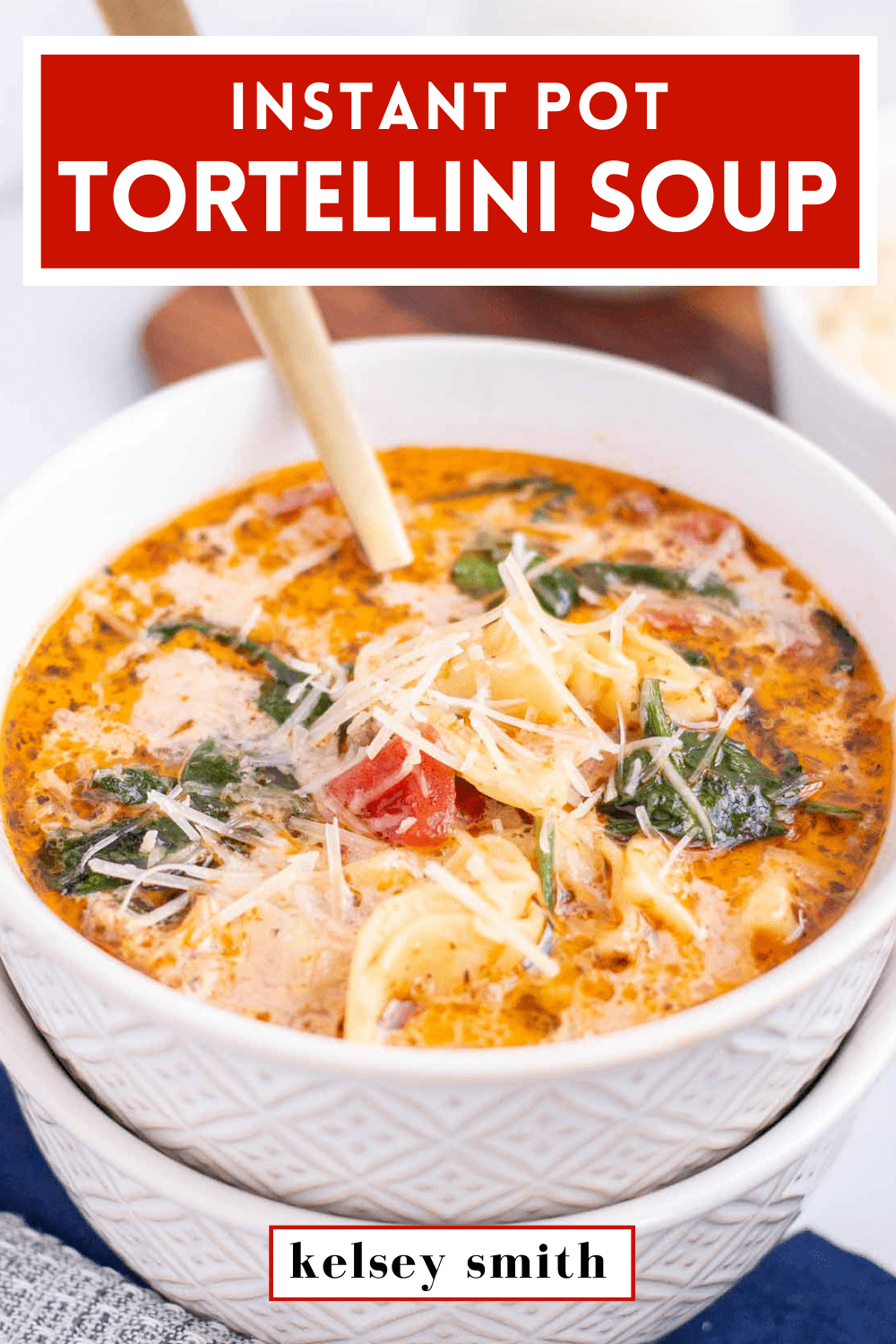 Top down view of Instant Pot tortellini soup with cheese tortellini, wilted fresh baby spinach, diced tomatoes, and a creamy broth in a bowl. Garnished with shredded parmesan.