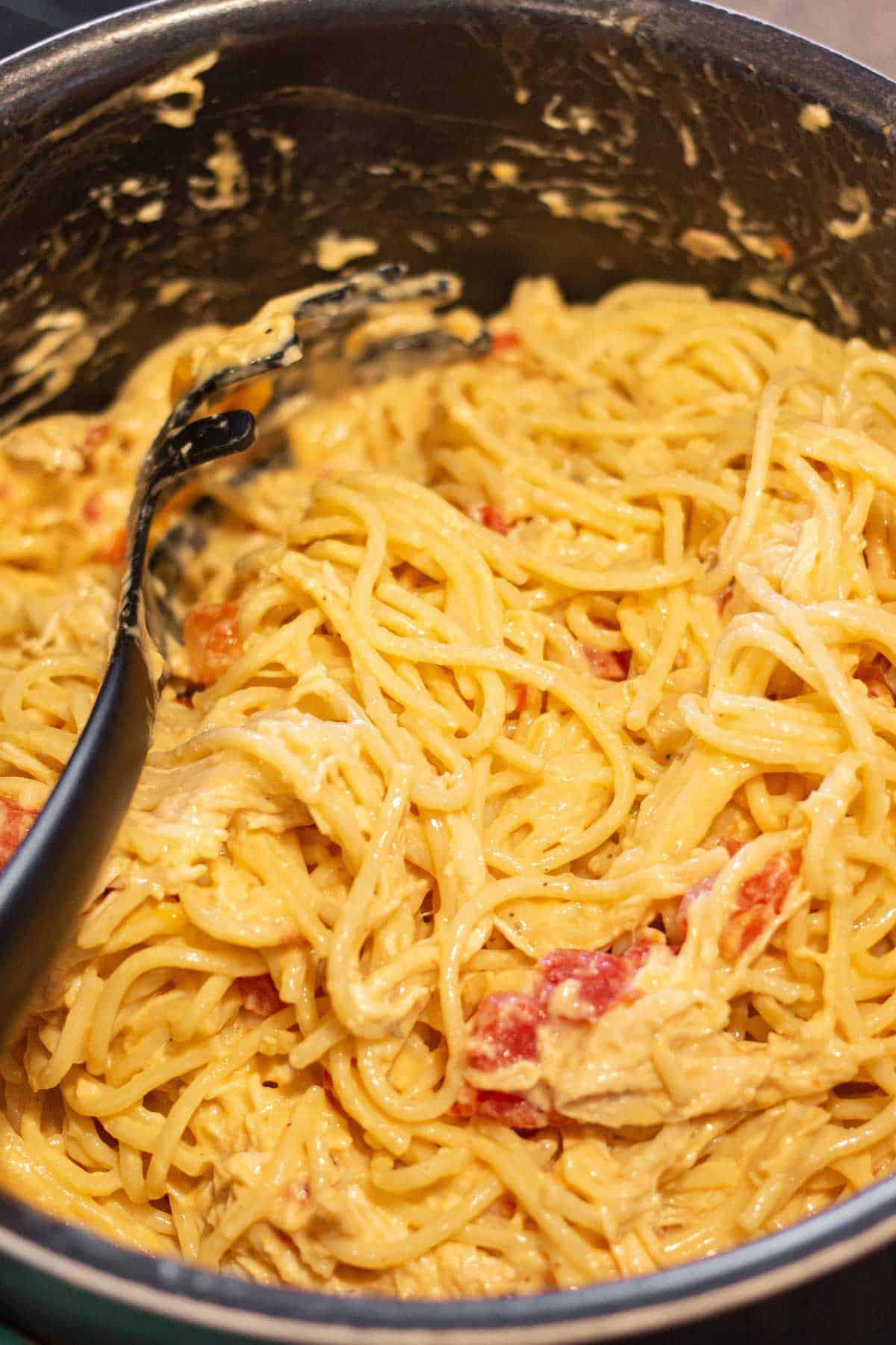 Cooked shredded chicken, al dente spaghetti, and the Rotel cheese mixture combined in a large pot.