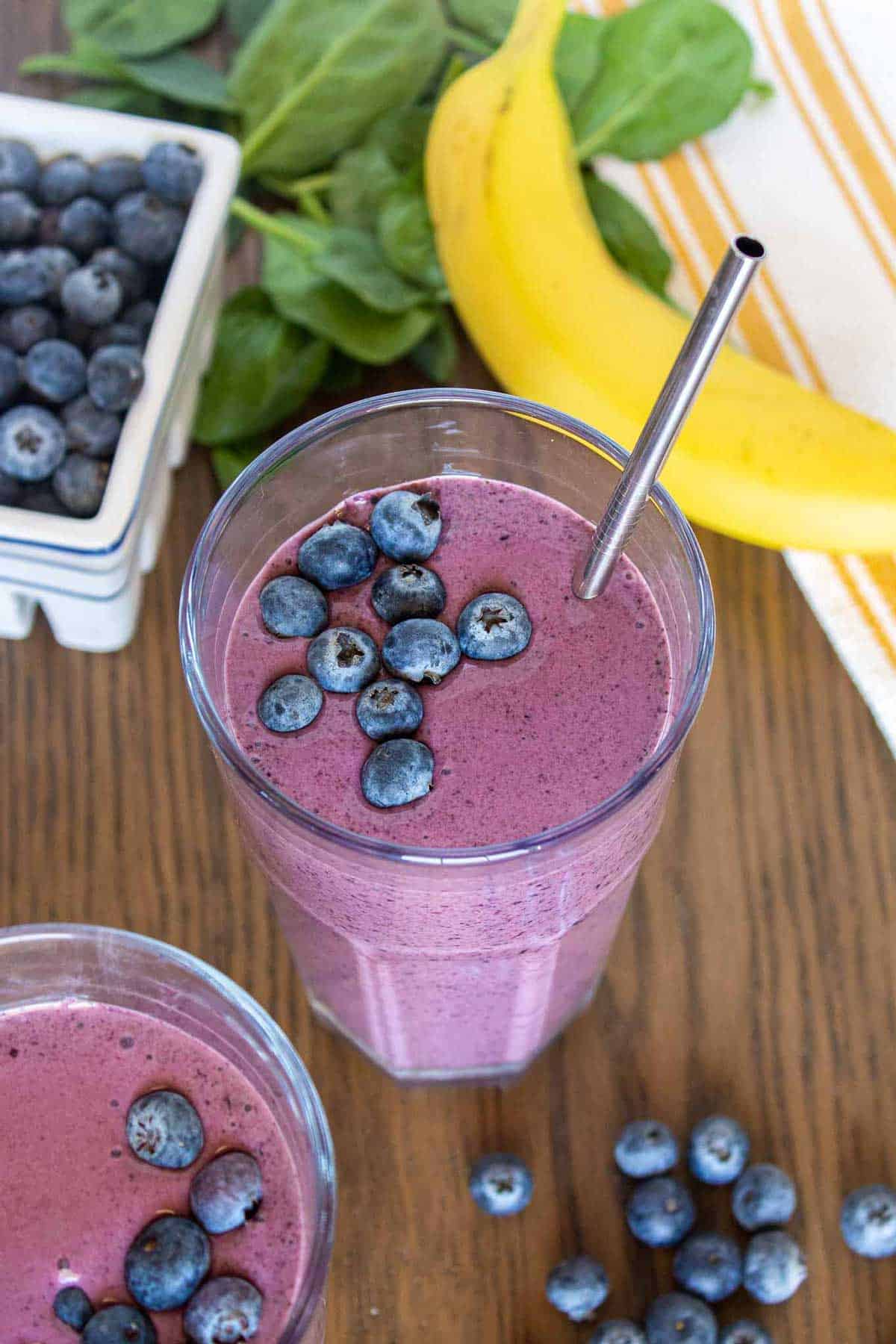 Blueberry banana spinach smoothie garnished with fresh blueberries