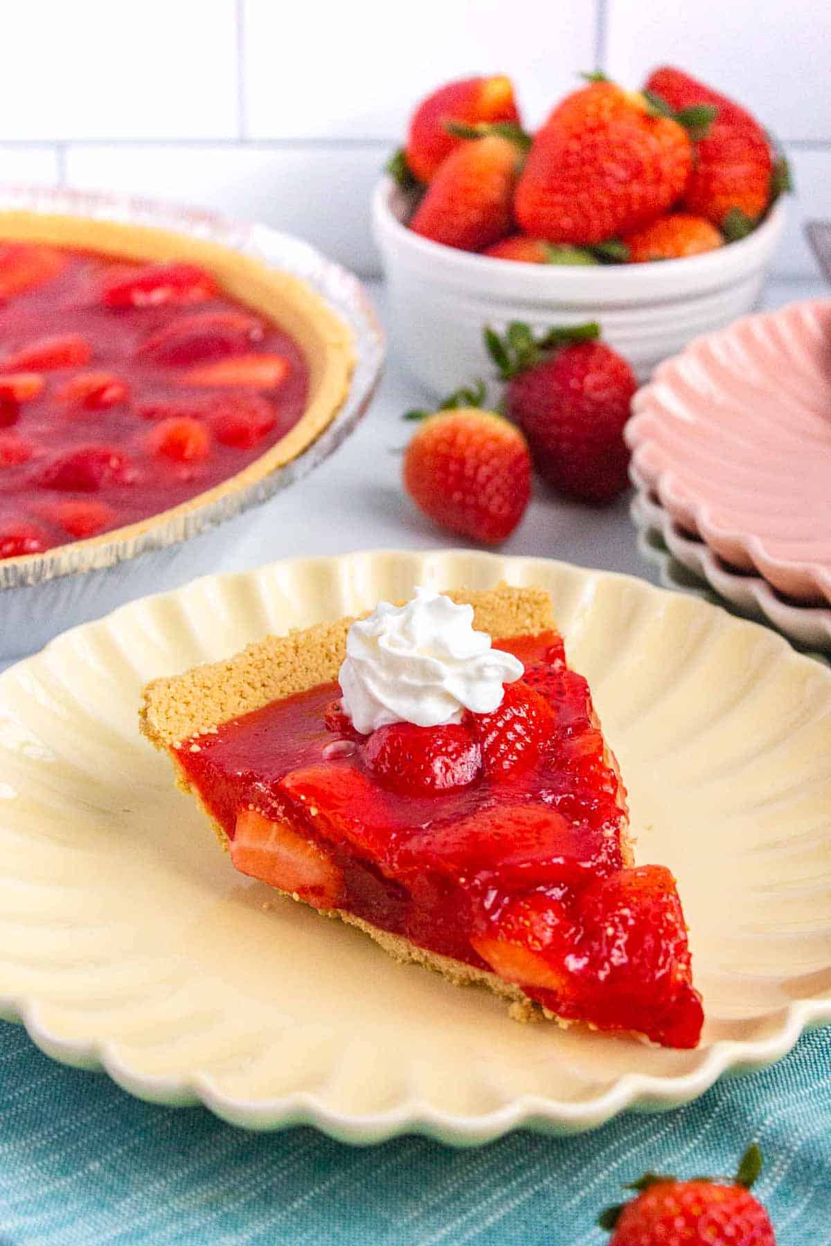 Slice of strawberry jello pie on a small plated topped with a dollop of whipped cream.