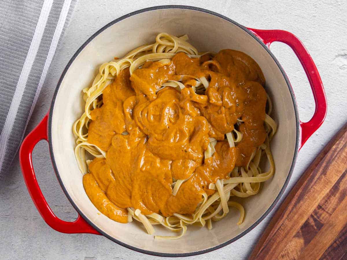 Avocado bell pepper sauce poured over fettuccine noodles in a large pot.