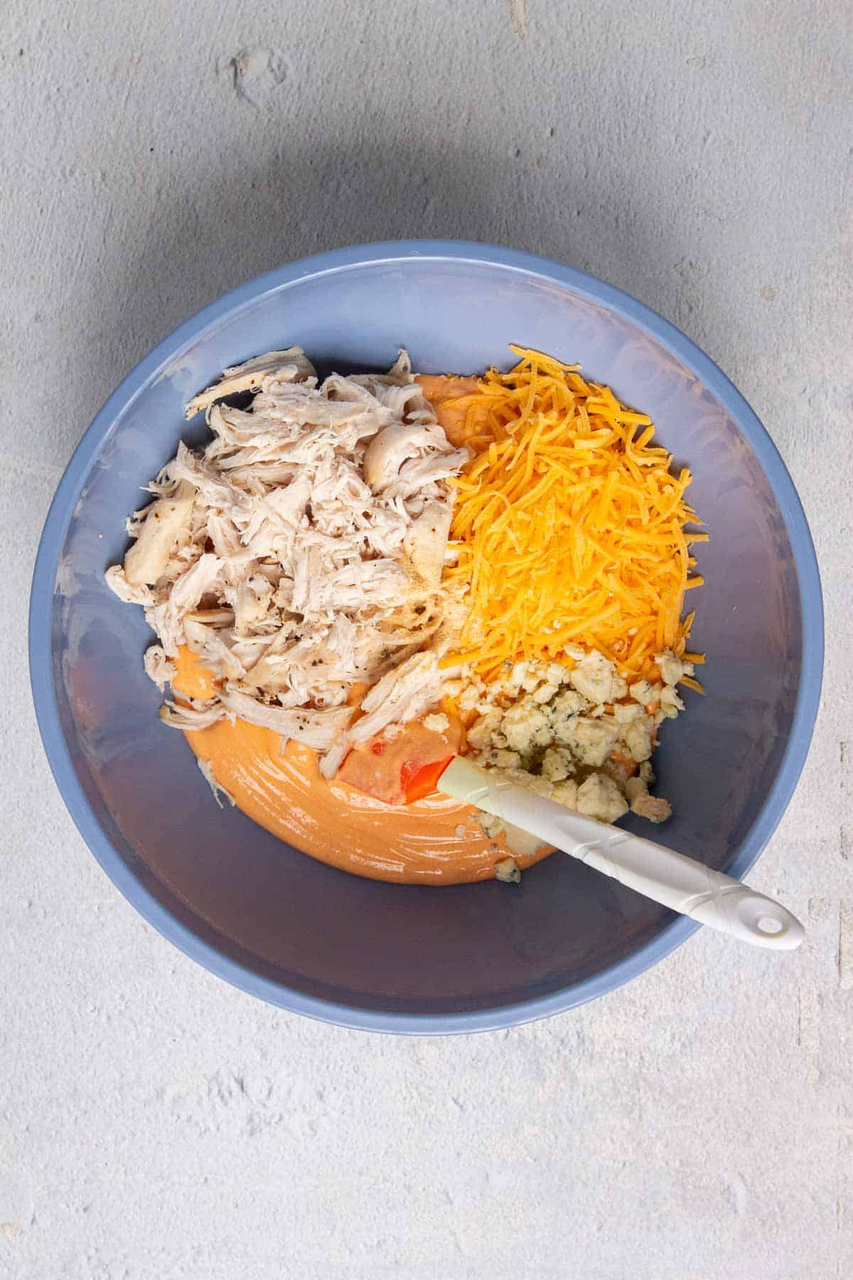 Healthy buffalo chicken dip ingredients in a mixing bowl.