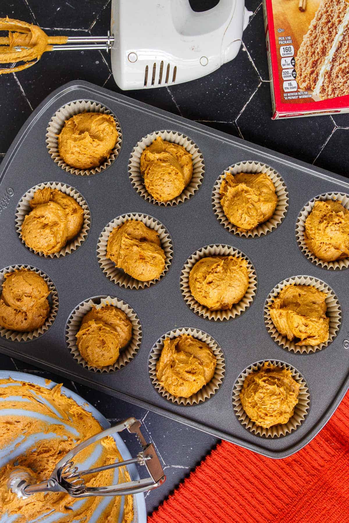 Pumpkin muffin batter distributed evenly in a lined muffin tin