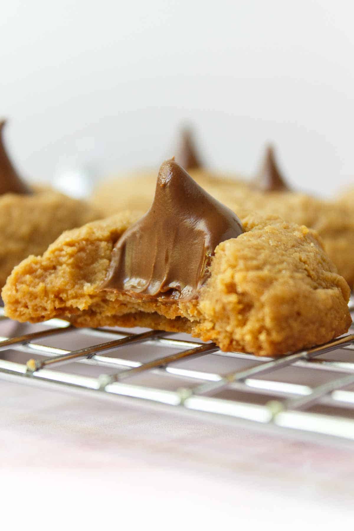 A bite is taken out of a peanut butter blossom cookie to show the creamy inside.