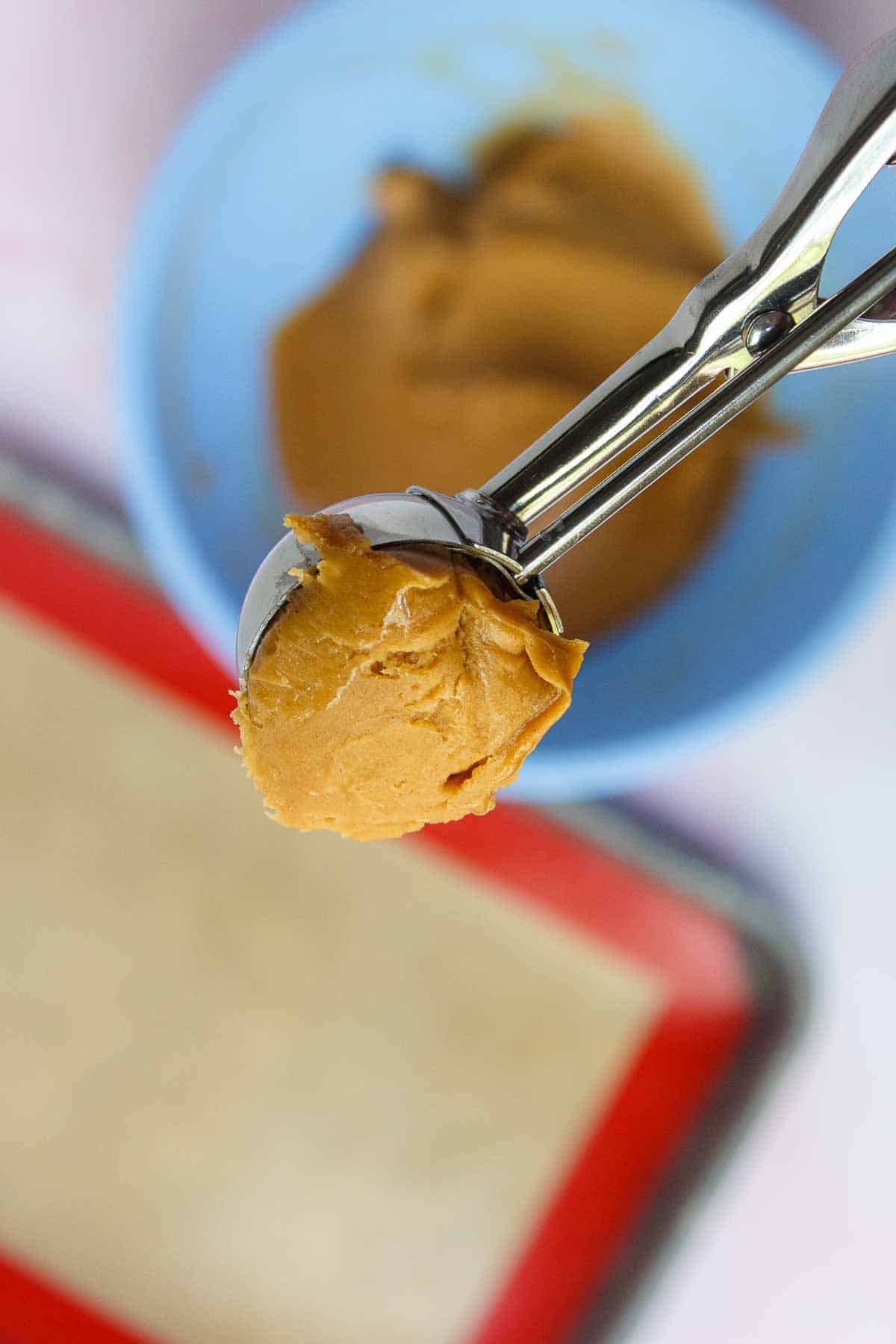 A tablespoon-size cookie scoop that is filled with cookie batter and slightly rounded.