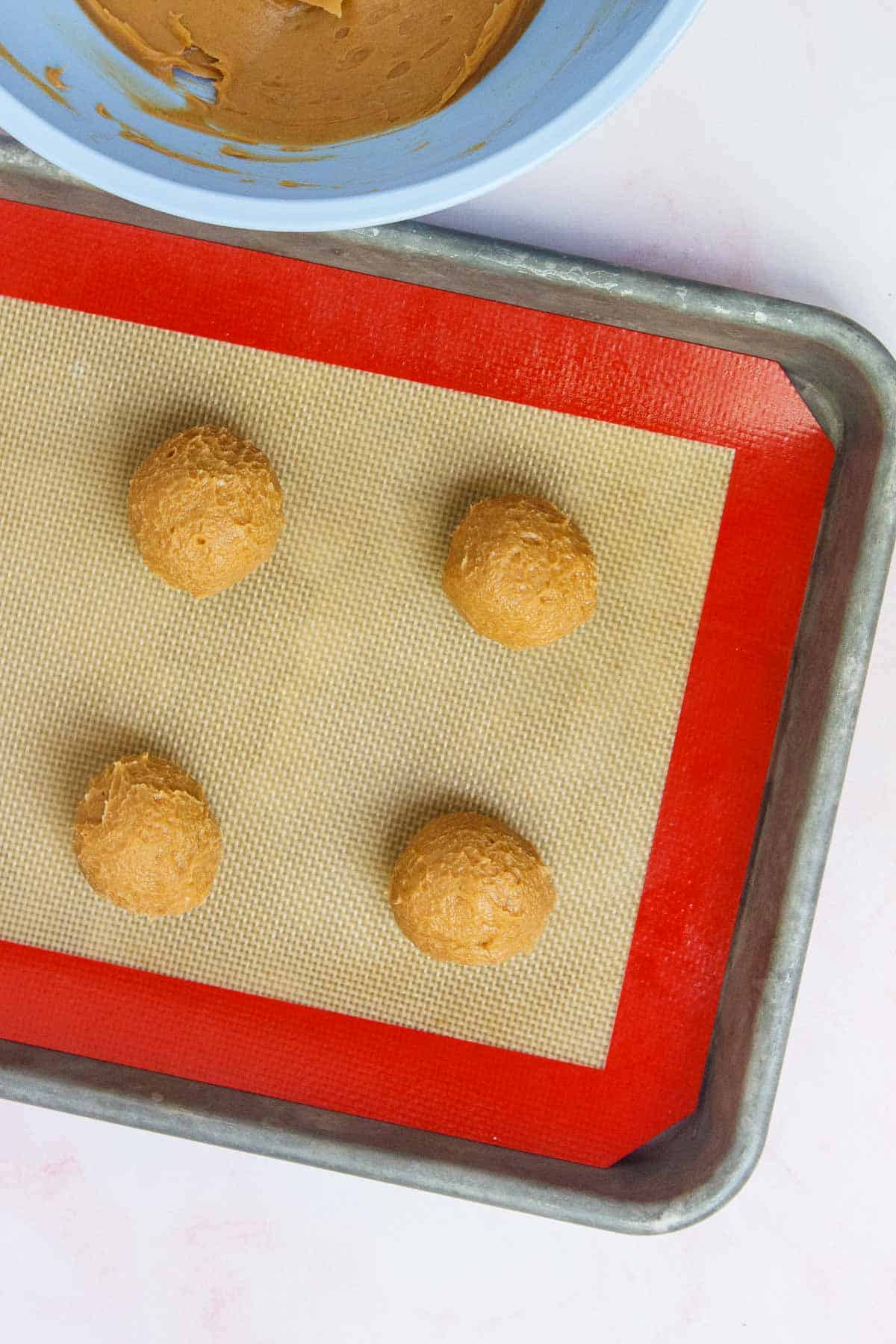 Cookie dough balls spaced evenly on a lined baking sheet.