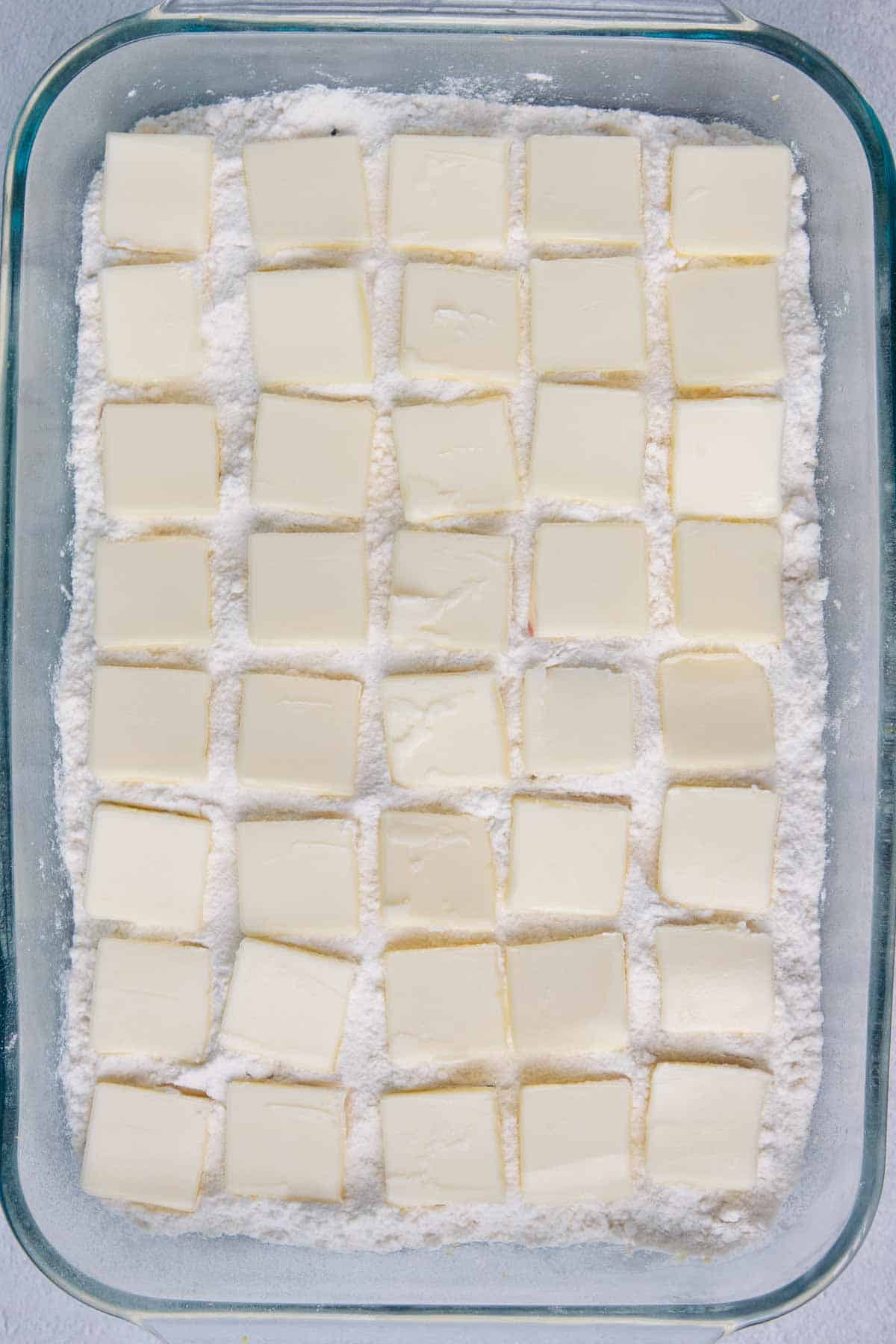 Thin butter slices distributed evenly on top of cake mix