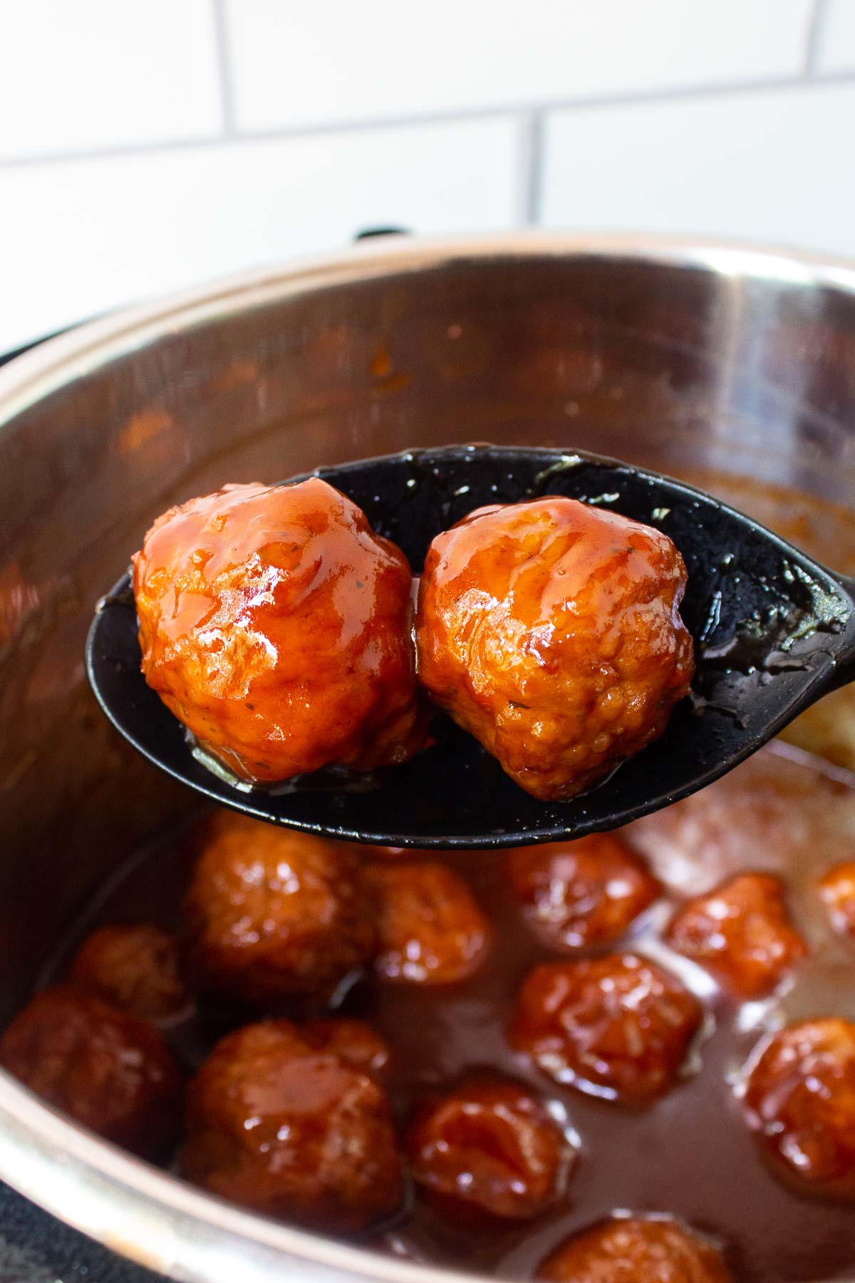 Two Instant Pot Grape Jelly Meatballs on a silicone serving spoon