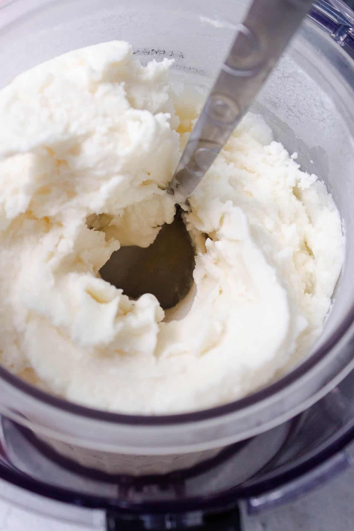 A hole is dug into the center of the vanilla ice cream pint using a spoon