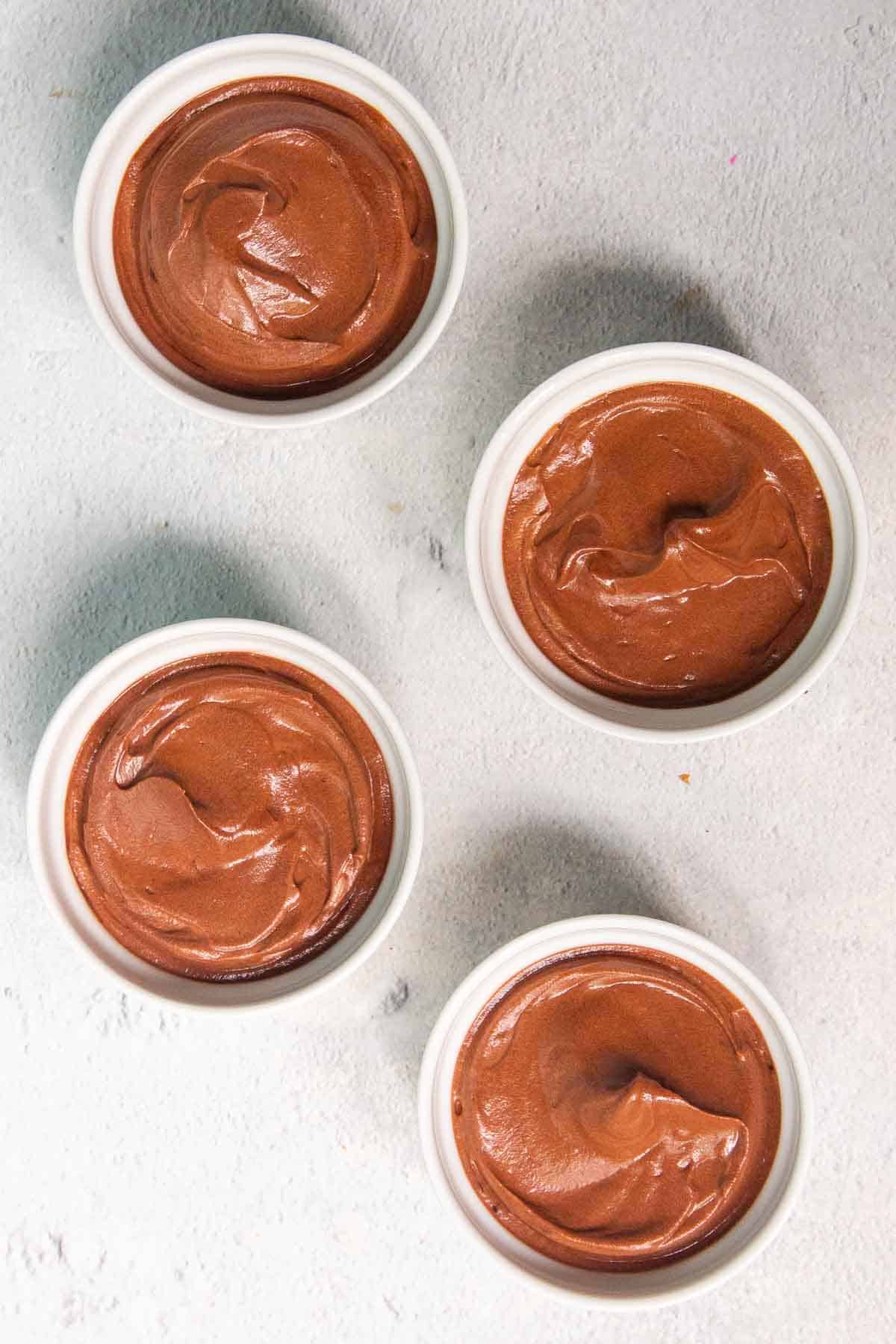 Chocolate mousse mixture divided evenly into four small ramekins