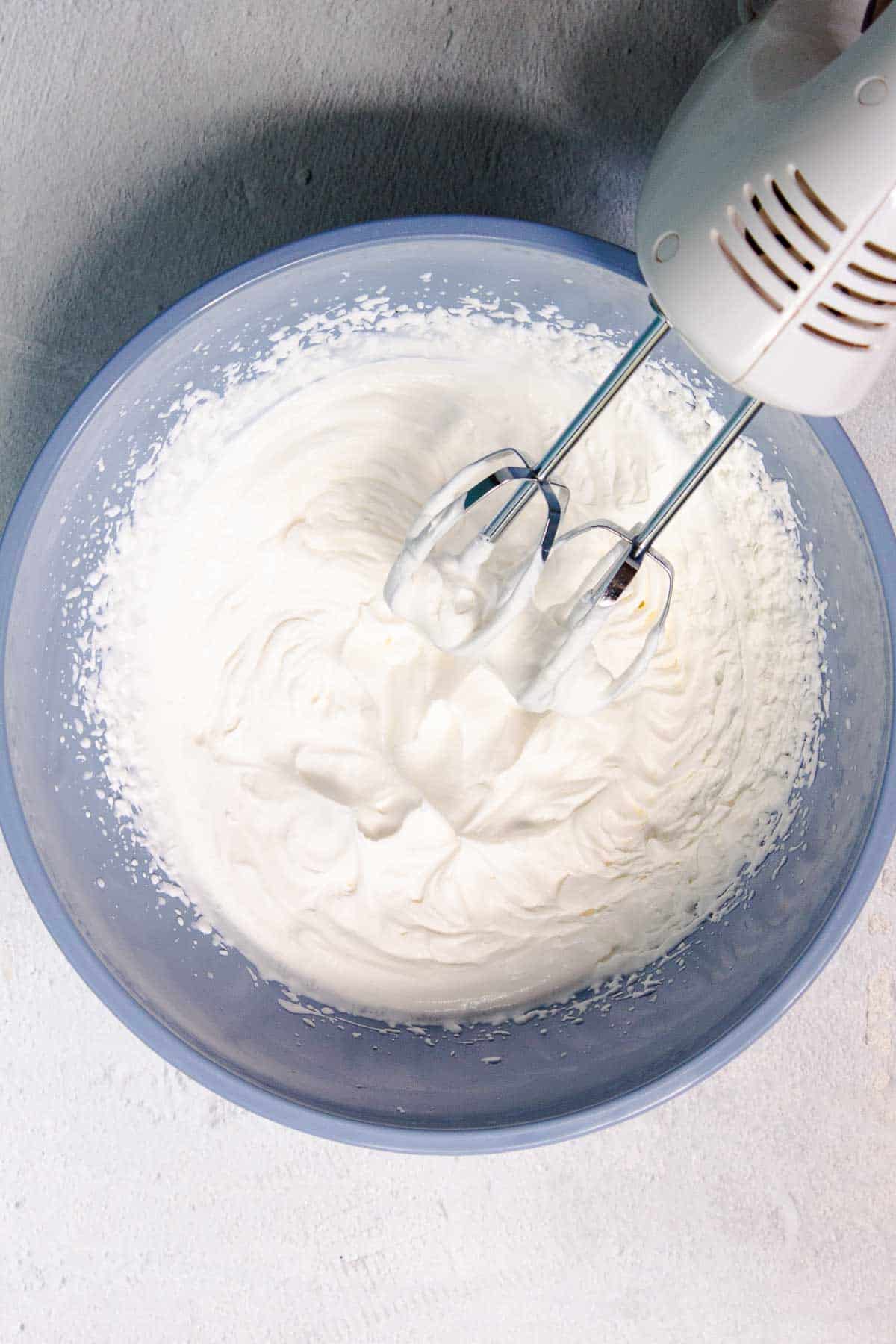 The heavy cream has been whipped with a hand mixer to create whipped cream