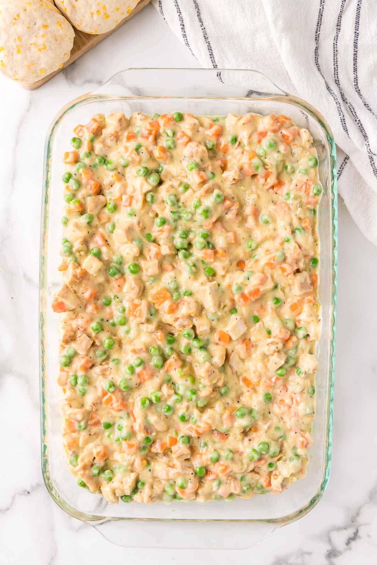 The chicken pot pie filling is spread evenly in a 9 by 13 inch baking dish