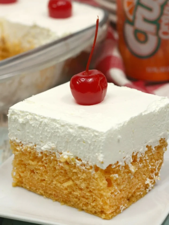 Slice of orange crush cake topped with a cherry