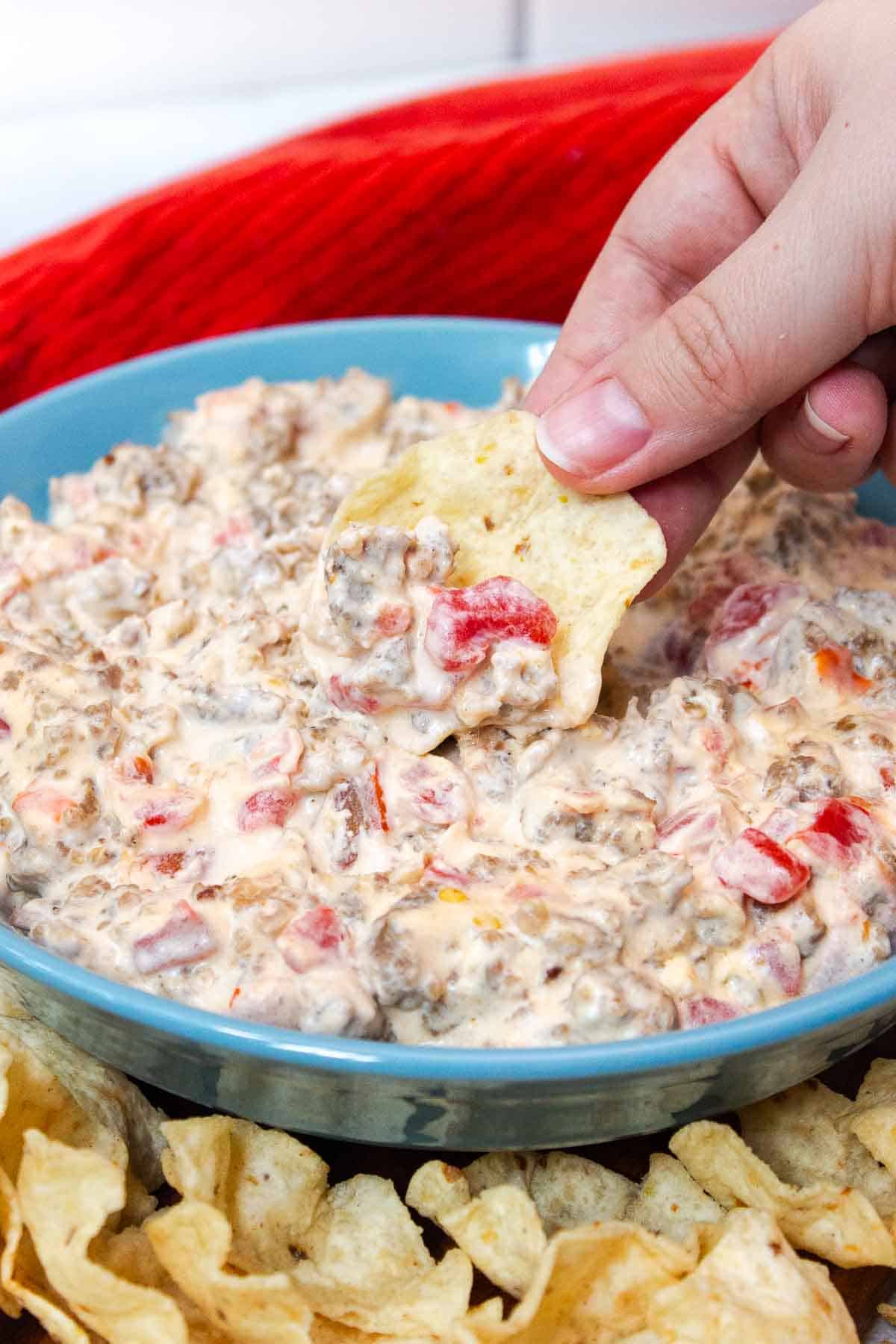 Tortilla chip scooping up cream cheese sausage dip to show chunky consistency