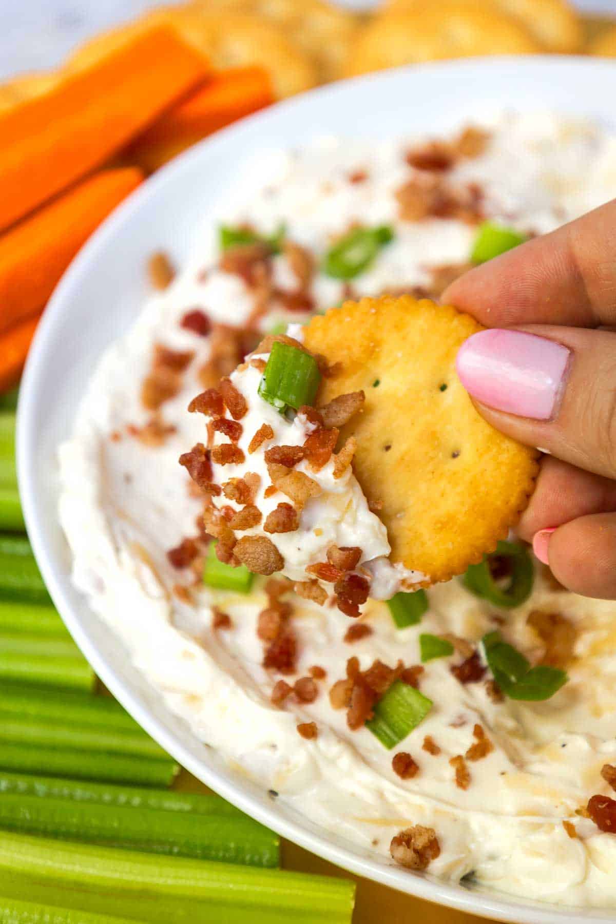 A Ritz cracker is topped with gouda dip.