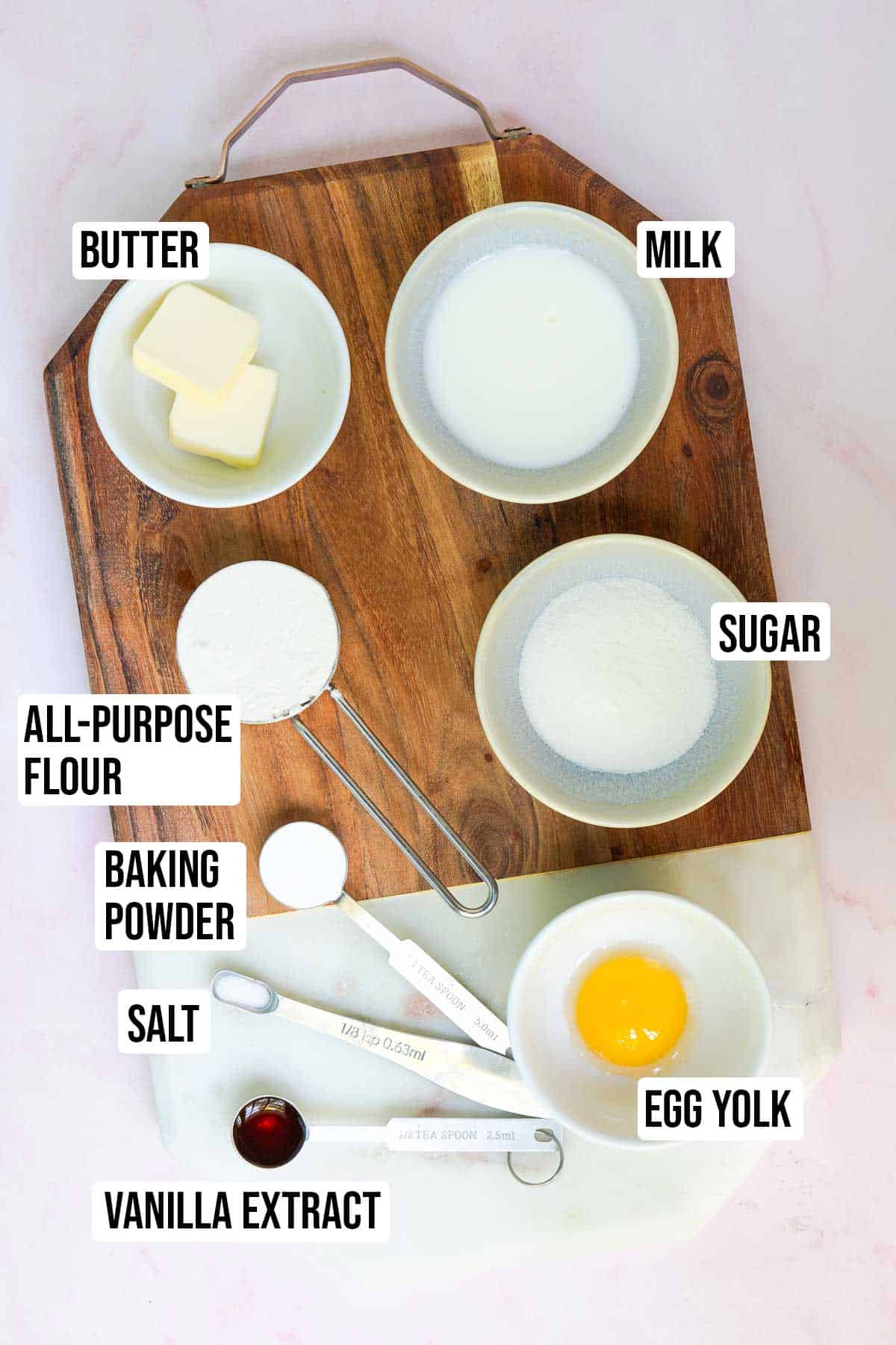 Yellow mug cake ingredients: butter, milk, vanilla extract, egg yolk, all-purpose flour, granulated sugar, baking powder, and table salt.