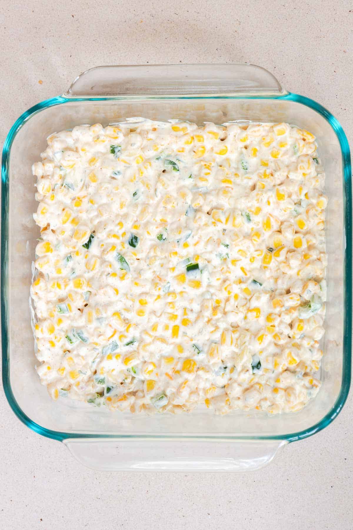 The cream cheese corn mixture is spread evenly in an 8 by 8 inch baking dish.