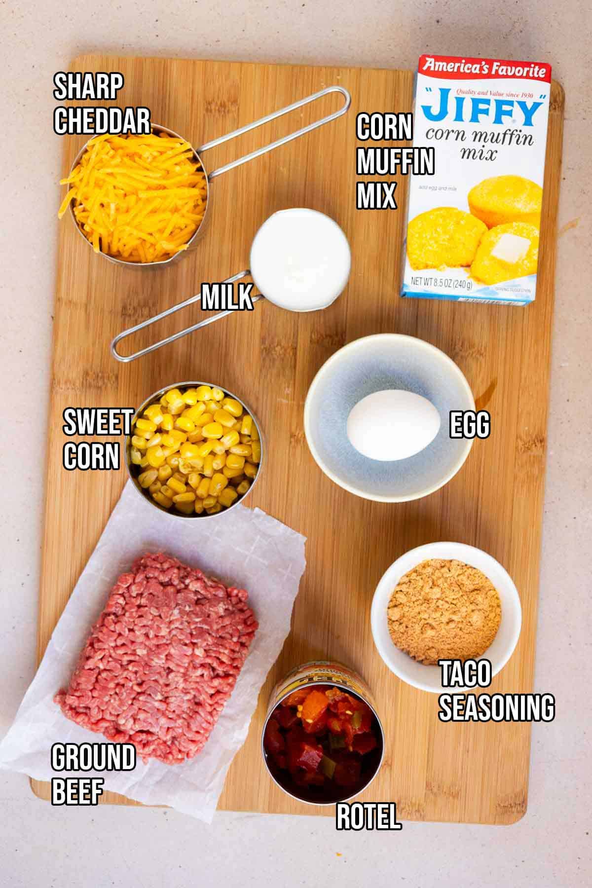 Mexican cornbread casserole ingredients: ground beef, Rotel, taco seasoing, Jiffy Corn Muffin Mix, milk, egg, sweet corn, and shredded cheddar.