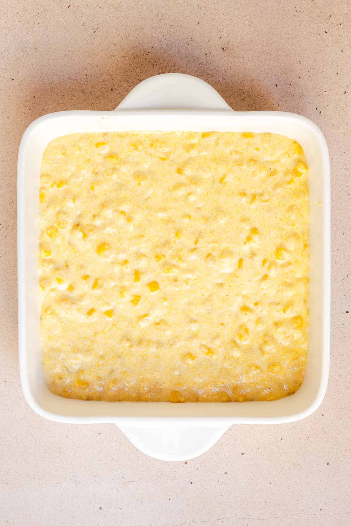 The cornbread mixture is spread evenly in the bottom on an 8 by 8 inch baking dish.
