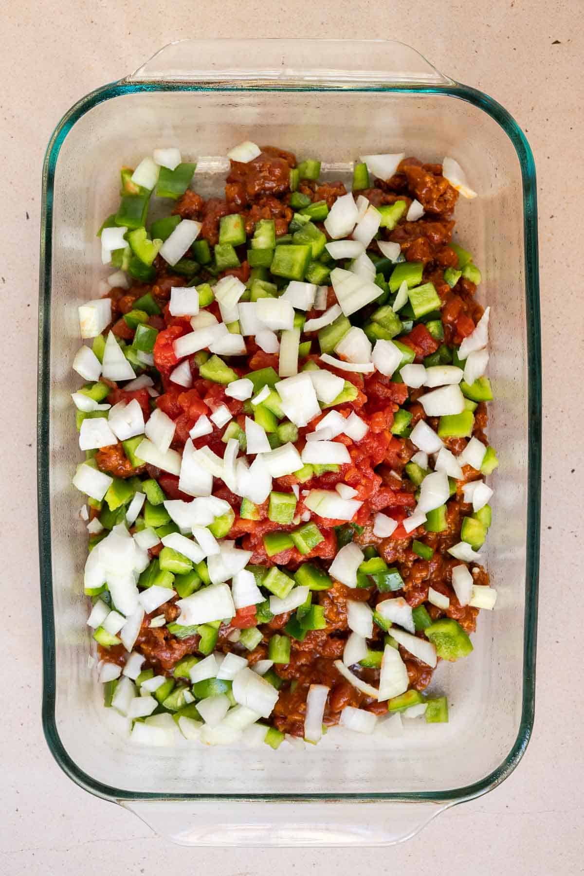 The canned chili and diced veggies are added directly to a 9 by 13 inch baking dish.