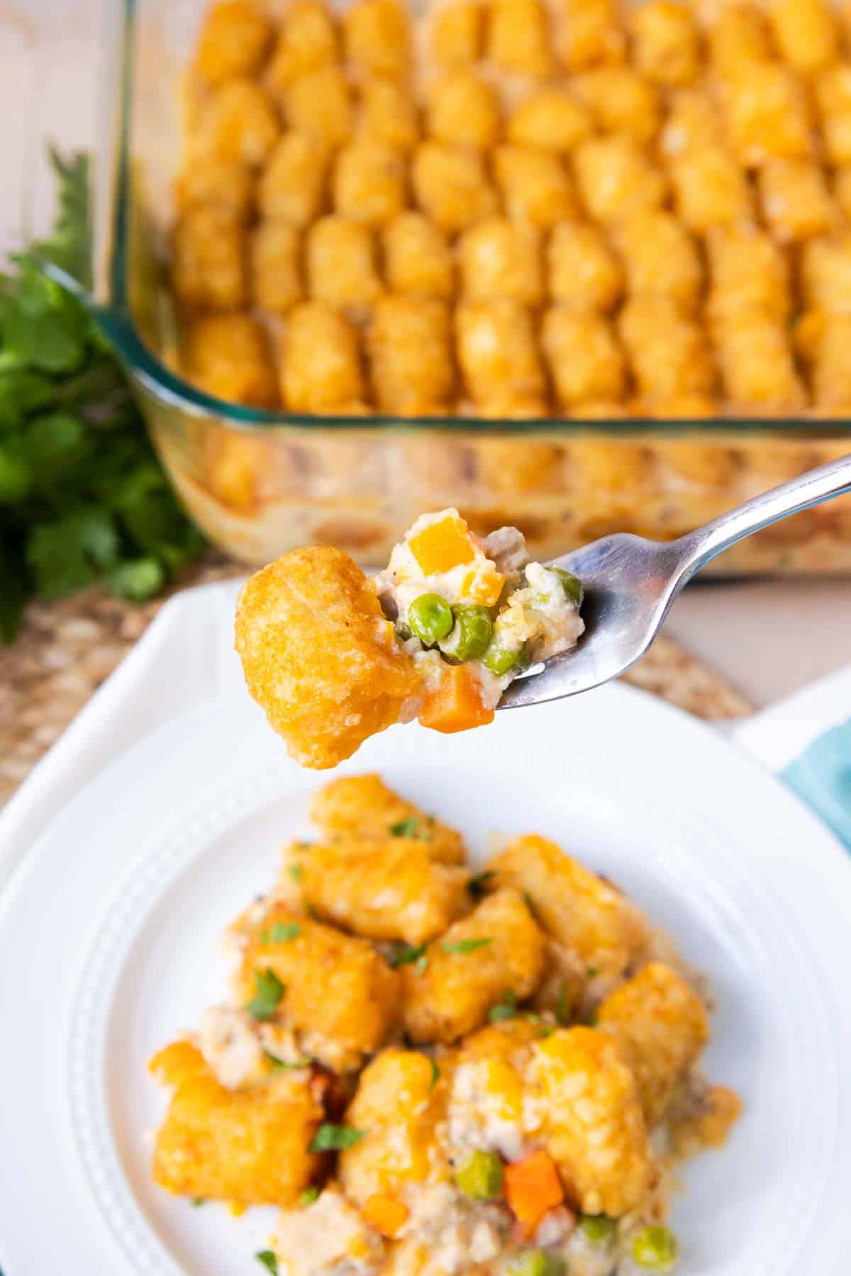 A forkful of Turkey Tater Tot Casserole to show the ground turkey, peas, and carrots in a creamy sauce.