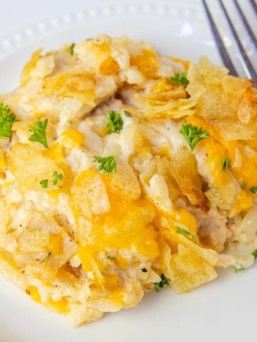 Potato chip chicken casserole is served on a plate and garnish with fresh parsley.