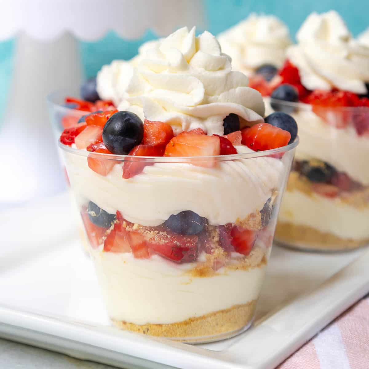 Layered no bake cheesecake cups with repeating layers of crust, cream cheese mixture, and berries.