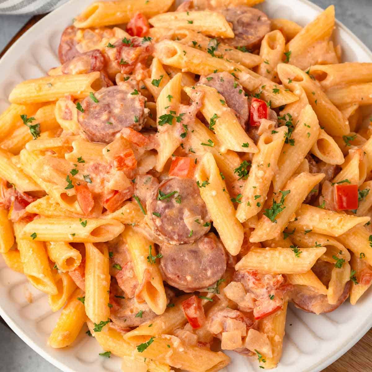 Pasta with sliced kielbasa, diced peppers, and diced onion in a creamy sauce.