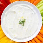 Creamy cottage cheese ranch dip on a serving platter with colorful fresh veggies including tri-color bell peppers, celery, and carrots.