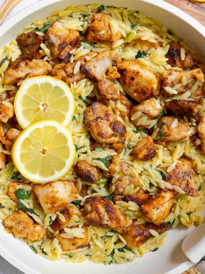 Lemon chicken orzo with diced chicken thighs and baby spinach in a large skillet.