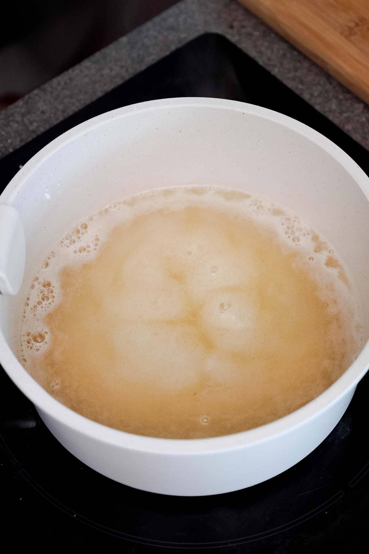 A white pot with a bubbling pale liquid.