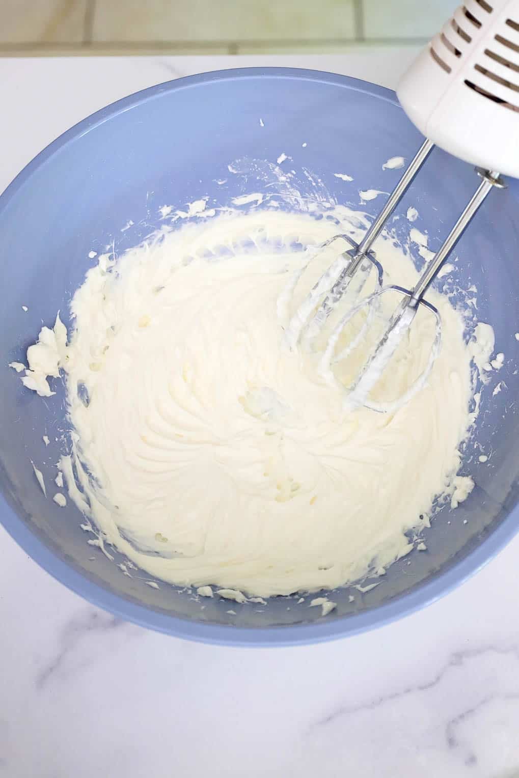 Cream cheese mixture whipped in a mixing bowl after beating with an electric mixer.