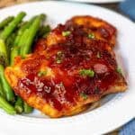 Oven baked BBQ boneless chicken thighs plated with green beans.