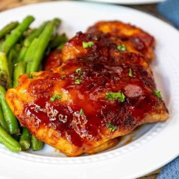 Oven baked BBQ boneless chicken thighs plated with green beans.