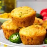 Close-up of a jiffy jalapeño cornbread muffin on a plate, with a focus on its golden crust and specks of jalapeño inside.
