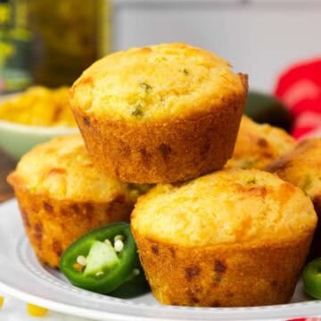 Close-up of a jiffy jalapeño cornbread muffin on a plate, with a focus on its golden crust and specks of jalapeño inside.