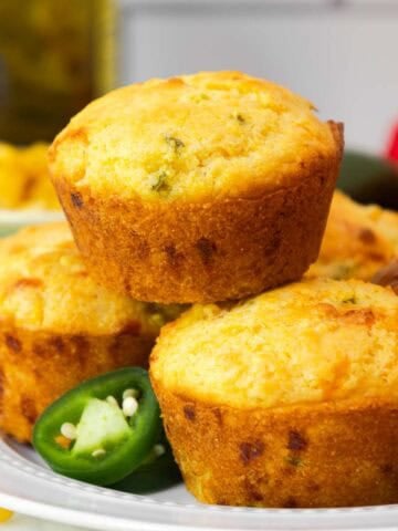 Close-up of a jiffy jalapeño cornbread muffin on a plate, with a focus on its golden crust and specks of jalapeño inside.