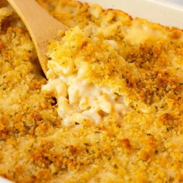 Baked gouda mac and cheese in a casserole dish with a wooden spoon scooping some out of the dish.