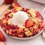 Strawberry dump cake topped with a scoop of vanilla ice cream.