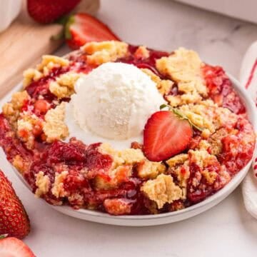 Strawberry dump cake topped with a scoop of vanilla ice cream.